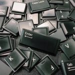 Close-up of scattered black computer keyboard keys on a surface, showcasing various letters and symbols.